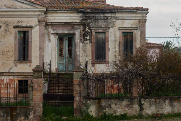 An abandoned house with boarded-up windows and rotting crumbling walls