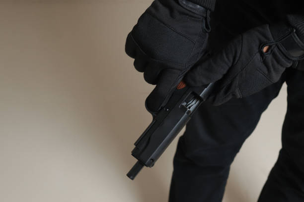 nahaufnahme der männlichen hand, die ihre pistole nach dem schießen nachlädt. isoliertes bild auf grauem hintergrund - bodyguard holding gun 20s stock-fotos und bilder