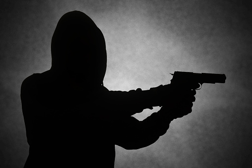 Portrait of a SWAT team soldier standing outdoors and aiming with a handgun.