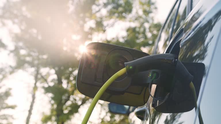 Hand putting a charger in an electric car, close up low angle shot