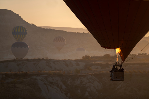 Closeup view of hot air balloon on blue sky background at sunrise. The balloon is flying over Goreme Historical National Park, Cappadocia, Turkey. Cappadocia is a popular tourist destination.