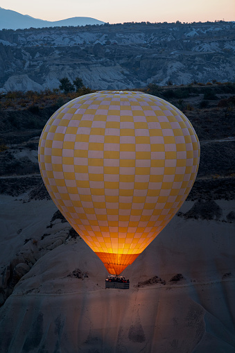Closeup view of hot air balloon on blue sky background at sunrise. The balloon is flying over Goreme Historical National Park, Cappadocia, Turkey. Cappadocia is a popular tourist destination.
