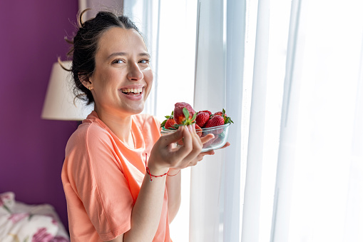 Who needs candy when you have fresh, sweet strawberries? This young woman is indulging in nature's candy in the kitchen