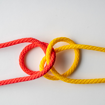 Close up photo of red and yellow colored threads knotted.