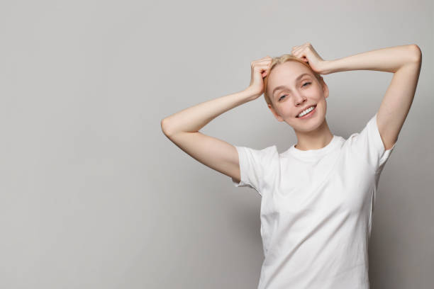 istock Joyful young woman wearing white empty t-shirt posing on grey studio background 1481077163