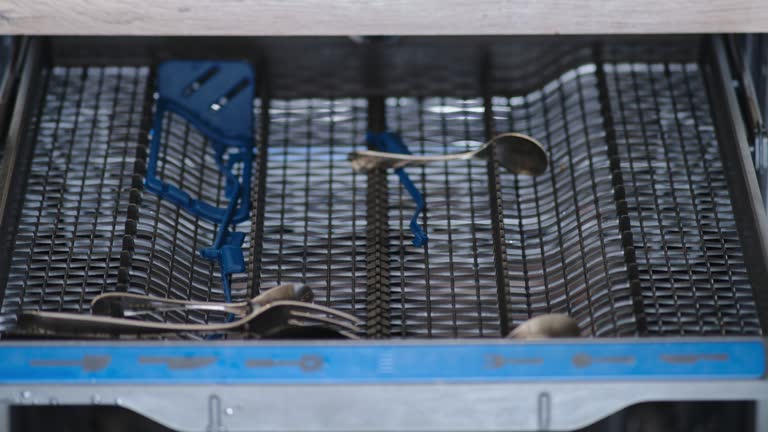 Unloading clean dishes from the dishwasher, stop motion. Removing spoon and fork from the dishwasher