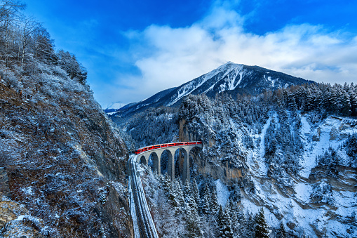 Landscape of Train passing through famous mountain in Filisur, Switzerland. Landwasser Viaduct world heritage with train express in Swiss Alps snow winter scenery.