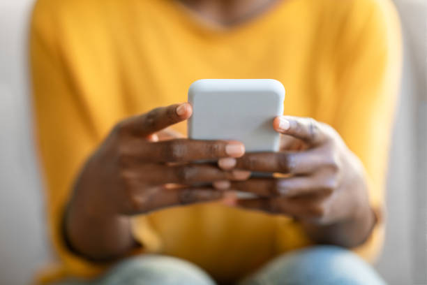 Hands of black woman using modern cell phone, cropped