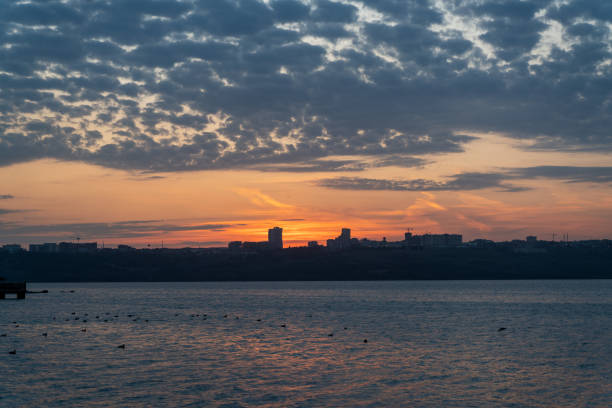 The beauty of the orange colors reflected in the lake as the sun sets behind the city.
