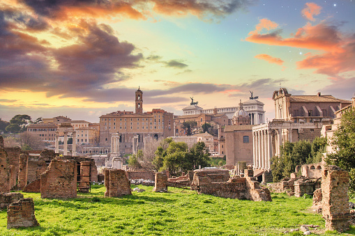 A wide view of the Forum Romanum in Rome Italy during a vivid sunset.