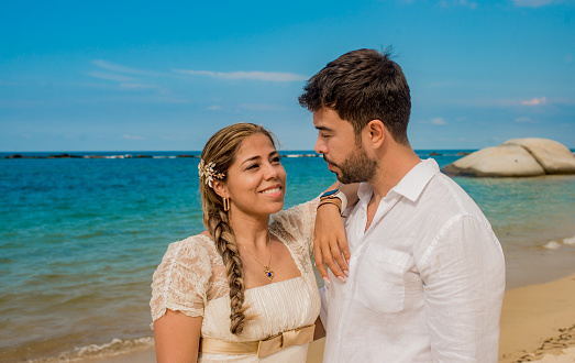 portrait of two people looking at each other on the beach in summer in white clothes