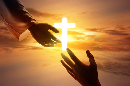 Jesus Christ giving a helping hand to humans with dramatic sky background