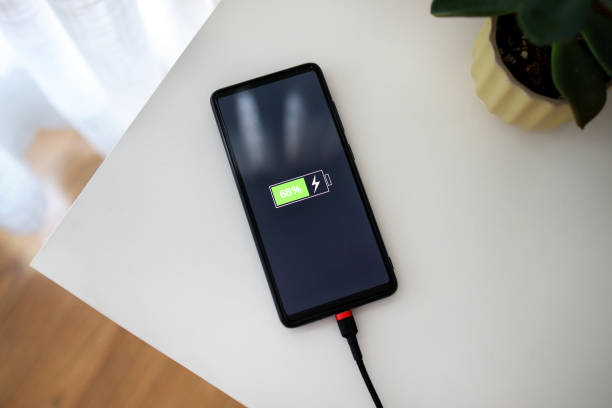istock Smart phone is charging with USB cable on the desk. 1481097195