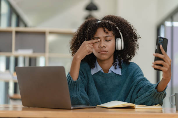 Female student in headphones holding smartphone, playing games and using mobile apps, online distance learning, watching video courses or zoom calls, making notes in workbook sitting at home. estudiante con auriculares sosteniendo un teléfono inteligente, jugando juegos y usando aplicaciones móviles, aprendizaje a distancia en línea, viendo cursos de video o llamadas de zoom, tomando notas en el libro de trabajo sentado en casa.