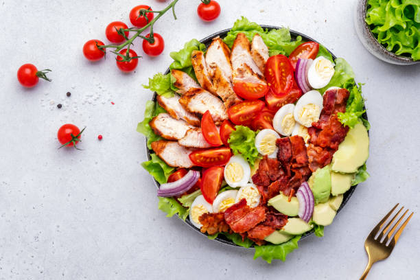 istock Cobb salad with chicken fillet, tomatoes, eggs, bacon, avocado and lettuce, gray table background, top view. American cuisine dish 1481101059