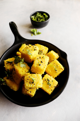 Indian chana Dal dhokla. Khaman dhokla is a famous dish of Gujarat. Made using rice, a healthy mix lentils and pulses, along with spices. garnished with coriander and fried chilies. Copy space