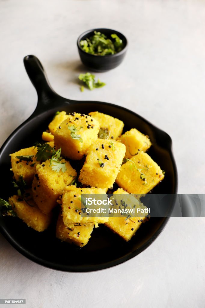 Indian chana Dal dhokla. Khaman dhokla is a famous dish of Gujarat. Made using rice, a healthy mix lentils and pulses, along with spices. garnished with coriander and fried chilies. Copy space Afternoon Tea Stock Photo