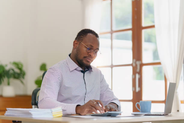 istock Smiling American African makes financial report and studies annual figures, analyzes profits. Accountant checks status of financial 1481106123