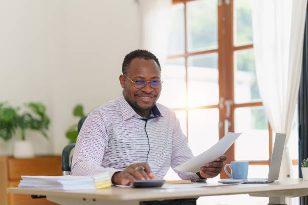istock Smiling American African makes financial report and studies annual figures, analyzes profits. Accountant checks status of financial 1481106182