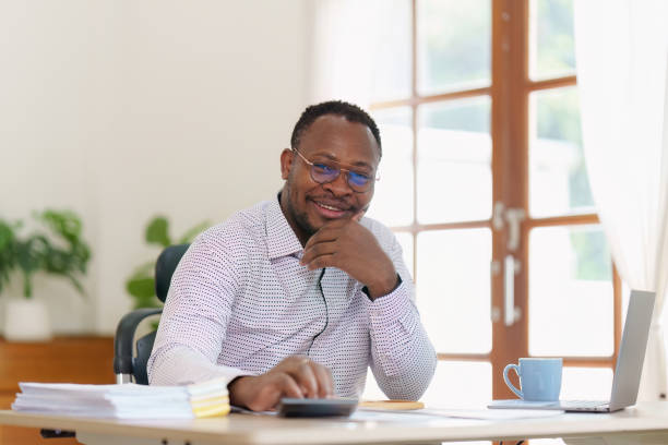 istock Smiling American African makes financial report and studies annual figures, analyzes profits. Accountant checks status of financial 1481106199