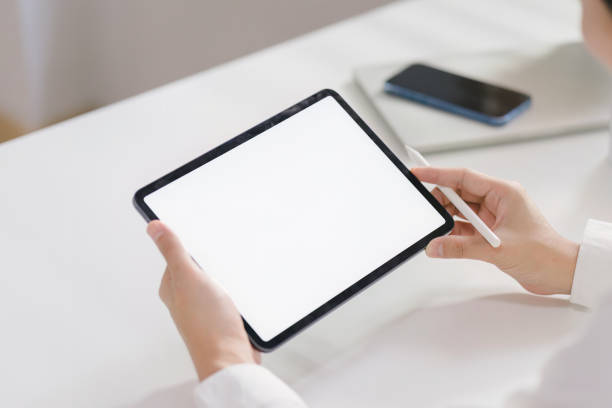 istock From a rear view, a businessman is seen holding and using a white screen digital tablet computer while sitting at his home office desk. 1481106948