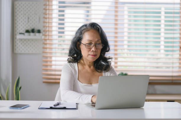 istock Happy mature old woman remote working from home distance office on laptop taking notes. Smiling 60s middle aged business lady using computer watching webinar and writing in notebook. 1481106961