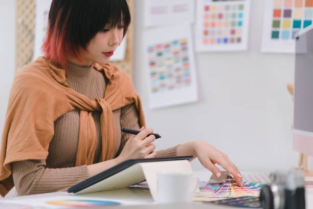 istock A creative and stylish young female freelance designer is using a tablet and stylus pen while sitting at her desk in office. 1481107384