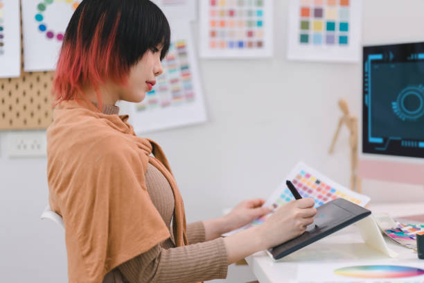 istock Young graphic designer using a tablet and stylus pen while sitting at her desk in office. 1481107396