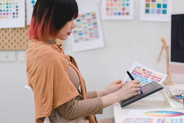 istock Young graphic designer using a tablet and stylus pen while sitting at her desk in office. 1481107399