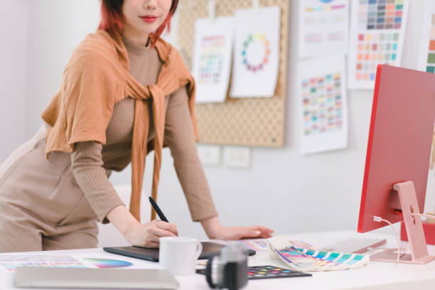 istock Young graphic designer using a tablet and stylus pen at her desk in office. 1481107402
