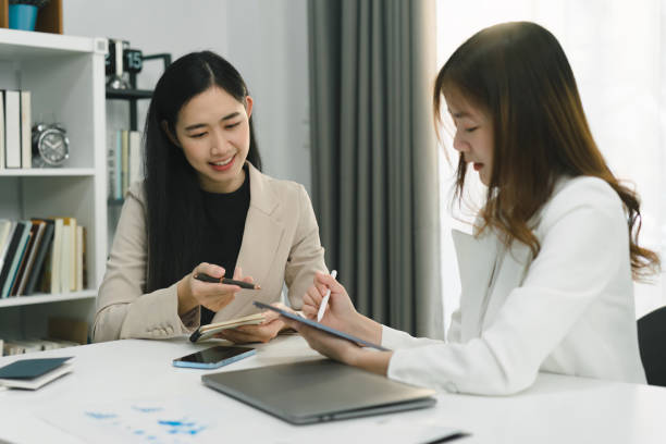 istock Two professional millennial Asian startup businesspeople are discussing evaluation data in a conference room, focusing on growth and pointing to a financial account chart,graph. 1481108026
