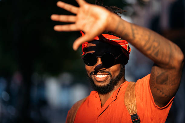 Stock photo of attractive young african american boy with his hand raised covering the sun.