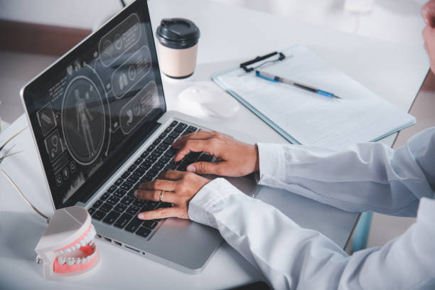 istock Dentist doctor or nurse in uniform use oral software teeth Xray and typing information medical history form into laptop 1481113002
