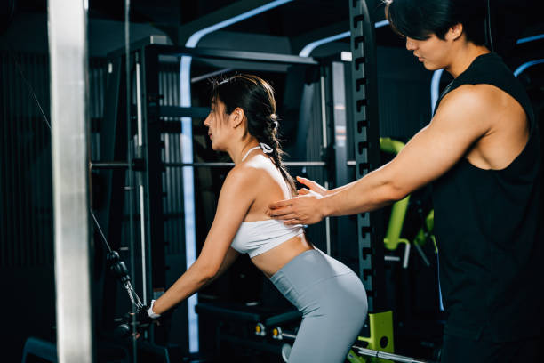 istock Male fitness coach teaching a woman how to use a pulldown cable machine 1481113092