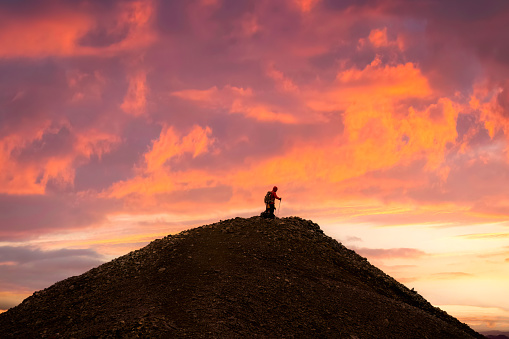 Group of hiker standing on top of volcanic mountain with colorful sky in the sunset among Icelandic Highlands in summer at Iceland