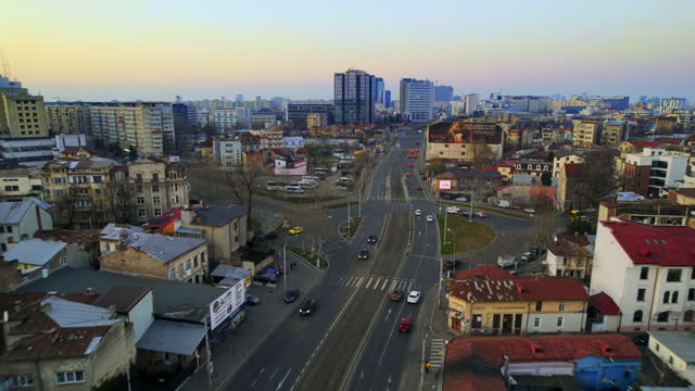 Aerial drone view of Bucharest at sunset, Romania. Multiple modern and old buildings, moving cars