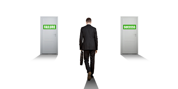 Rear view of male manager carrying a suitcase while standing on an intersection with a success and failure door isolated over white background