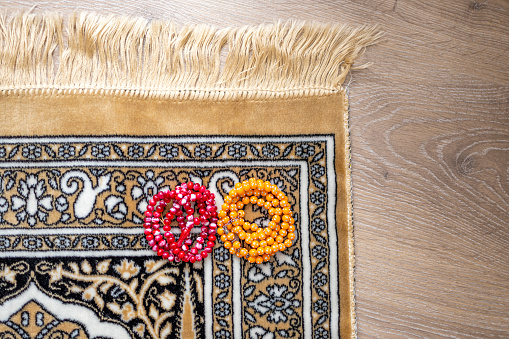 Red and orange rosary on prayer rug