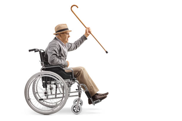 elderly man sitting in a wheelchair and holding a cane - physical injury men orthopedic equipment isolated on white imagens e fotografias de stock