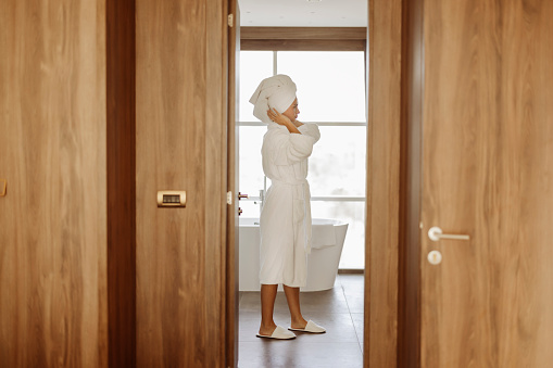Caucasian woman in towels standing in bathroom after shower
