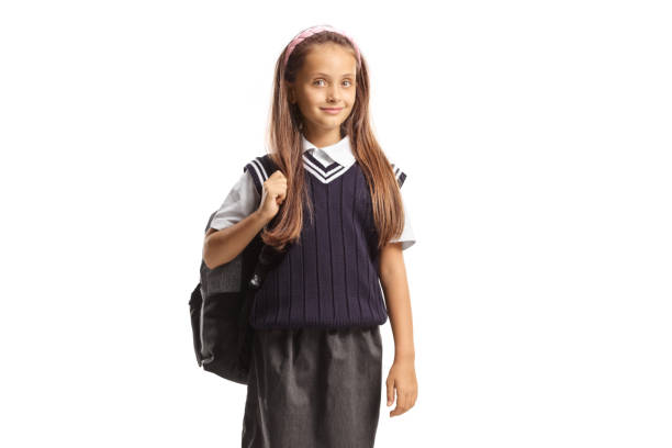 Schoolgirl in a uniform carrying a backpack isolated on white background