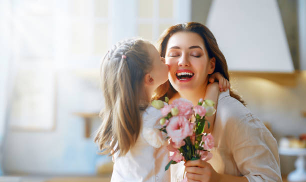 Daughter giving mother bouquet of flowers. stock photo