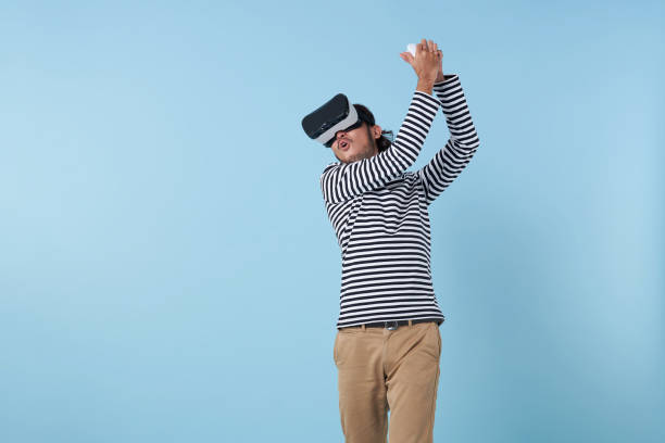istock asian man playing a game in virtual reality. Active young man play golf while wearing virtual reality goggles. Sporty young man exploring immersive virtual reality games. 1481131388