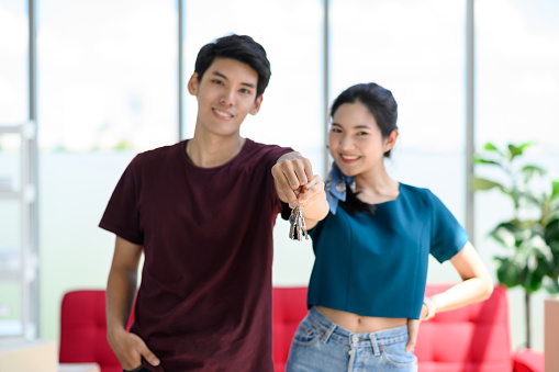 Young Asian couple move into new apartment on Moving Day, celebrating moving to new home concept