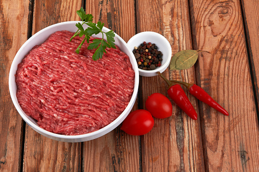 Fresh pork and beef minced meat on a wooden background.