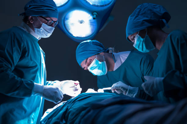 Group of concentrated surgical doctor team doing surgery patients in hospital operating theater. Professional medical team doing critical operations. Group of concentrated surgical doctor team doing surgery patients in hospital operating theater. Professional medical team doing critical operations surgery stock pictures, royalty-free photos & images