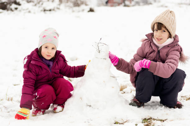 istock Girls making snowman during winter day on the meadow 1481136435