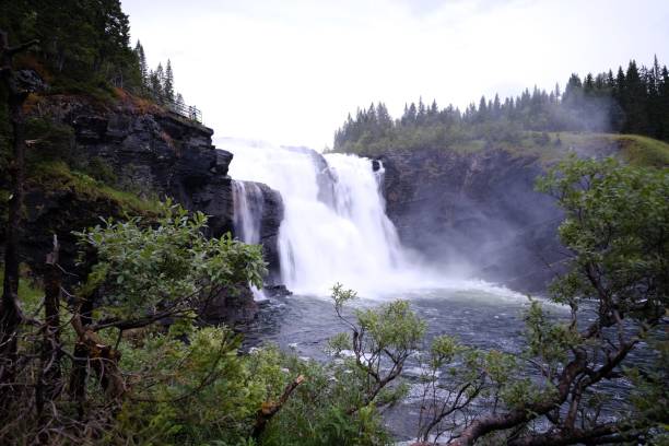 istock a waterfall sits below trees, in the mountains near to an overcast sky 1481137597
