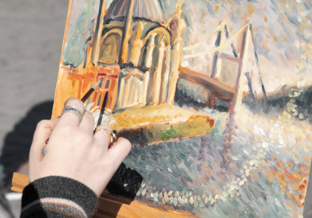 Older man between 55-60 enters his closed-door studio to create art and make a painting on canvas, while the afternoon falls and the shadows of the sun are seen on the window that gives a nostalgic atmosphere to his creation