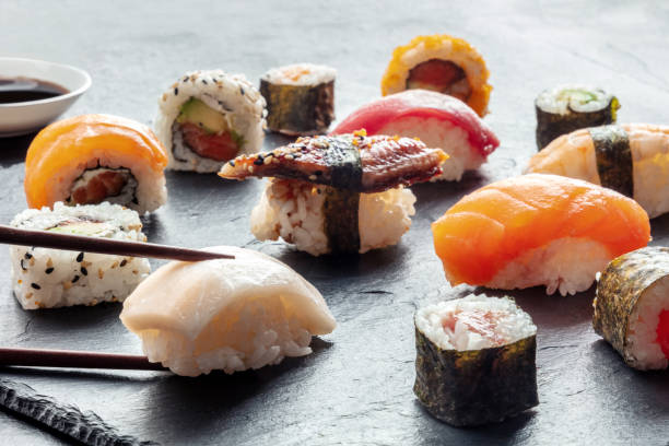 istock Sushi with chopsticks on a black slate background. Rolls, maki, nigiri 1481143485